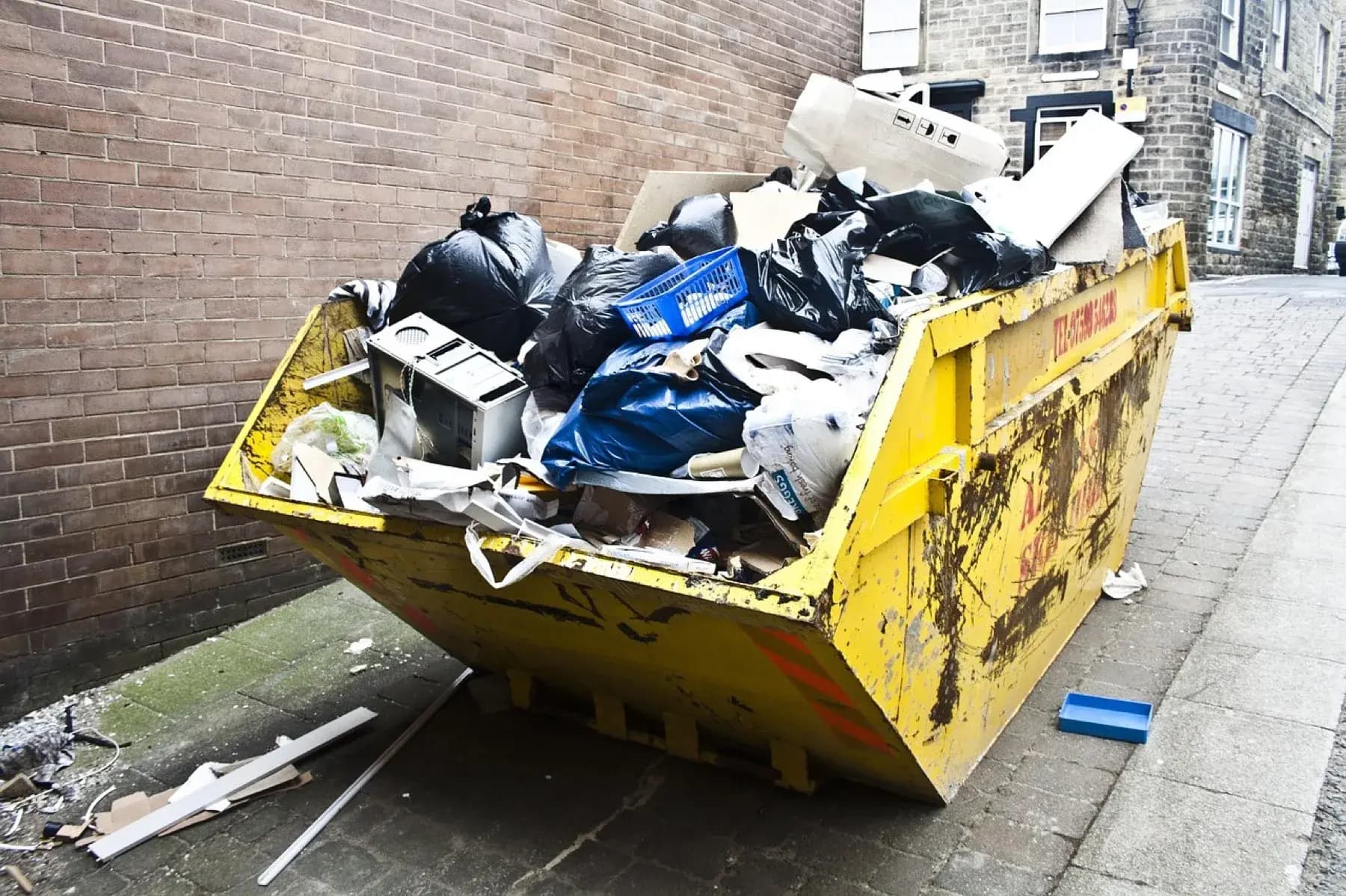 Yellow skip bin overflowing on an urban street — street-placement permit context